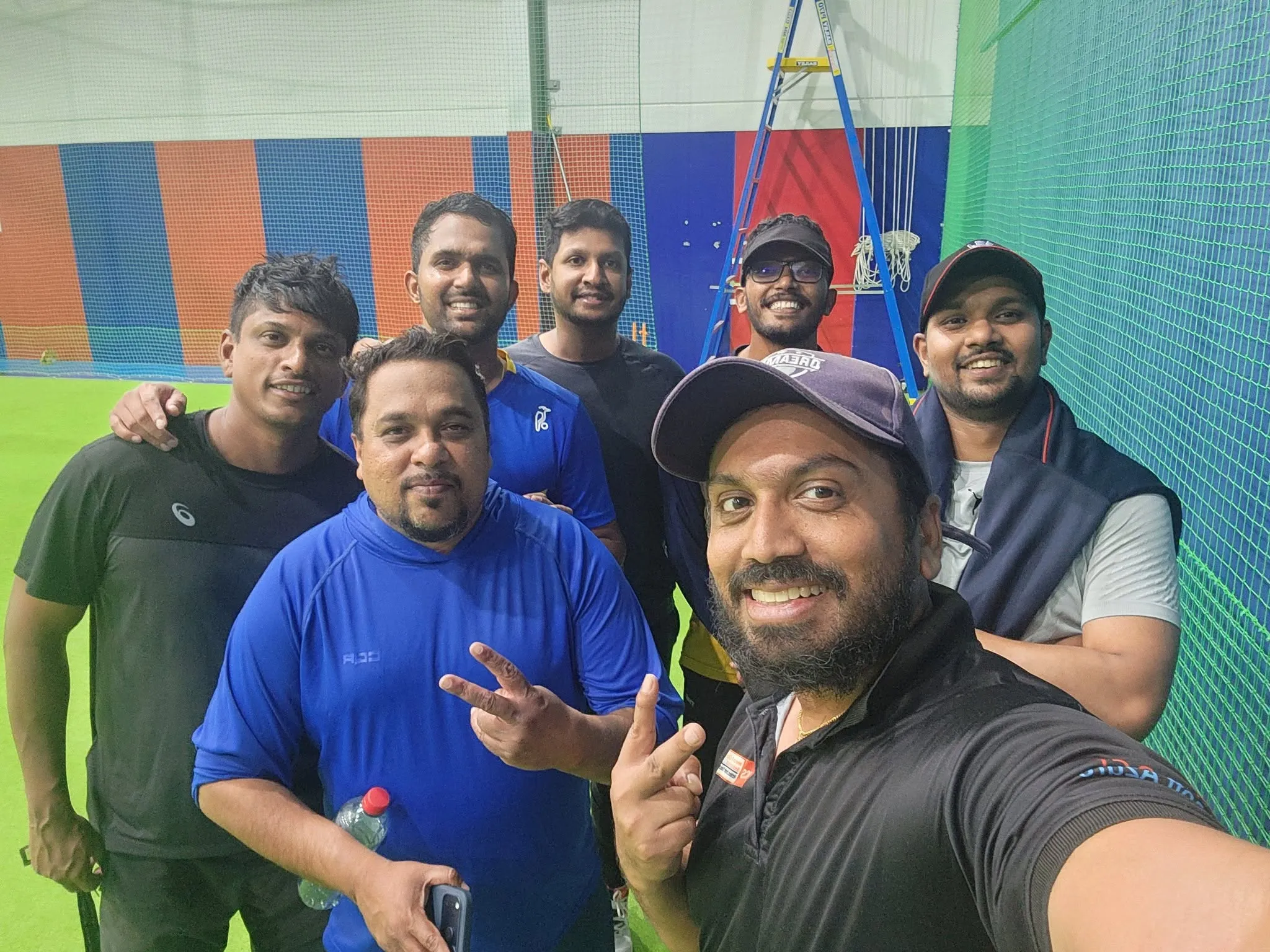 Seven Dreamers players crowded together for a photo inside the practice nets after a training session.